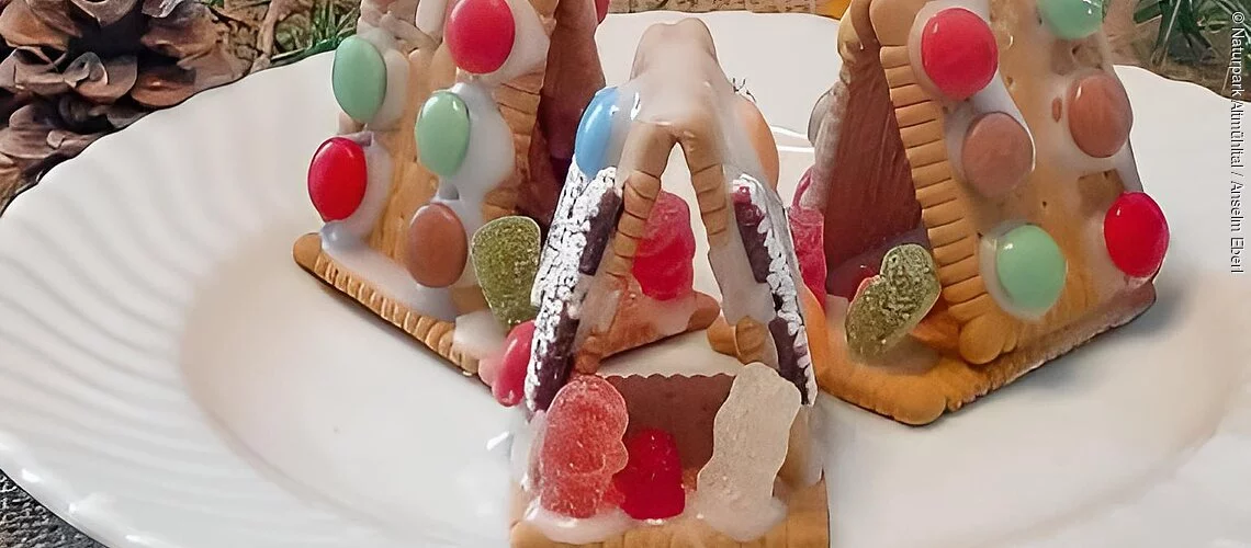 Drei Kekskrippen aus Butterkeksen auf einem Teller, Weihnachtlich dekoriert
