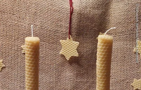 Bienenwachskerzen 2 selbstgemachte Bienenwachskerzen weihnachtlich dekoriert mit Zapfen und Walnüssen, im Hintergrund Sternanhänger aus Bienenwachs