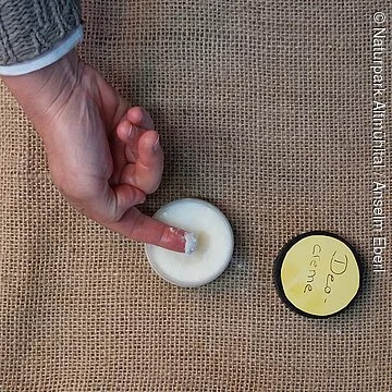 Deocreme fertig Ein Finger wird in ein Döschen mit selbstgemachtem festen Deo gesteckt.
