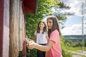 Nahaufnahme eines spielenden Mädchens an der Klangstation. Zweites Mädchen im Hintergrund.