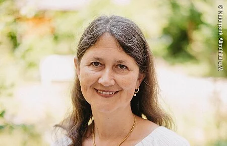 Ilonka Luidl Frau mit weißer Bluse vor grünem Hintergrund