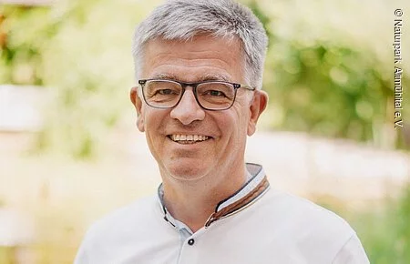 Christoph Würflein Mann mit Brille und weißem Hemd vor grünem Hintergrund