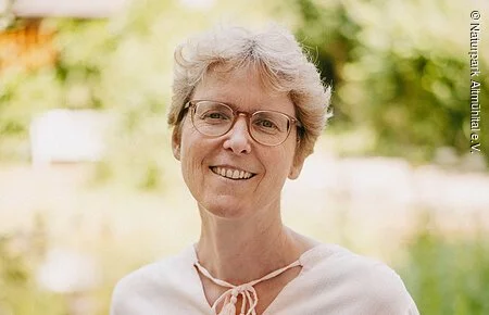 Christa Boretzki Frau mit heller Bluse vor grünem Hintergrund