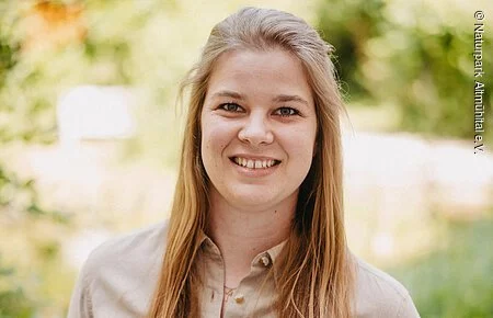Katja Müller Frau mit hellem Hemd vor grünem Hintergrund