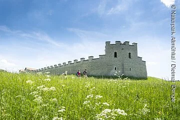 Das Römerkastell rekonstruiert mit weißen Steinen inmitten einer grünen Wiese.