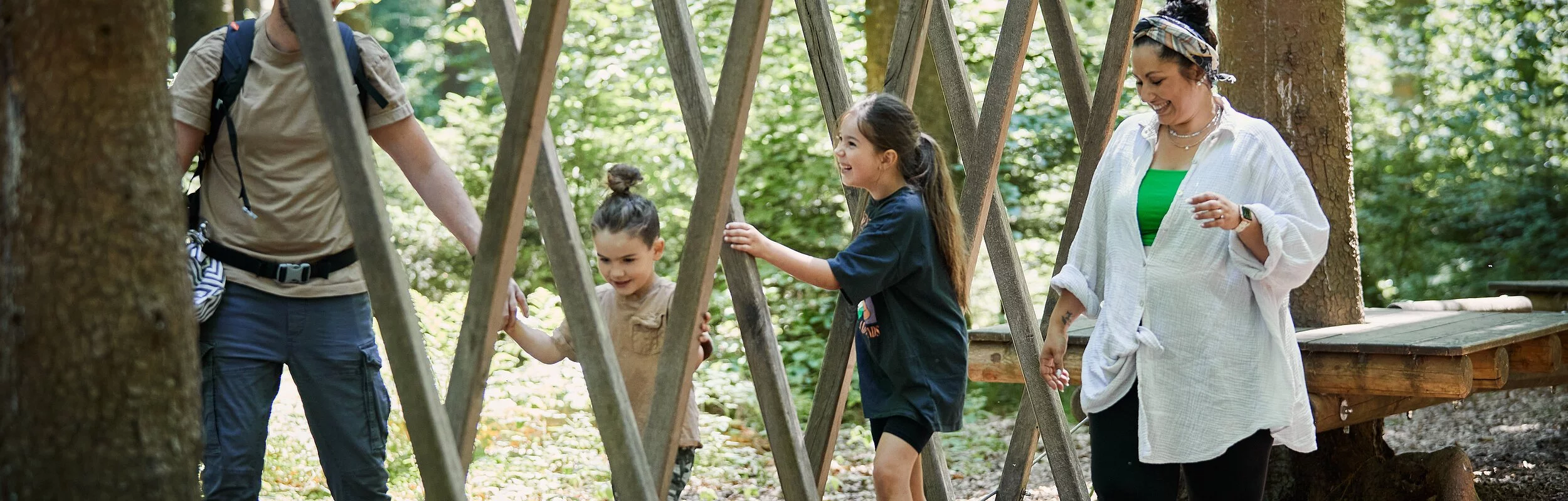 Eine Familie mit zwei Kindern sind im Holzparcours am Walderlebniszentrum unterwegs.