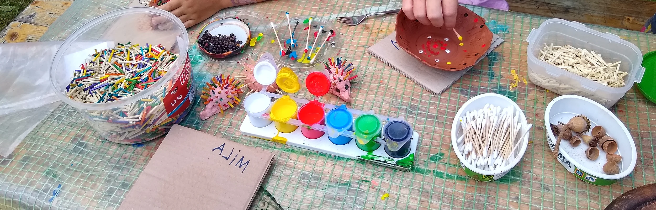 Kind bastelt mit Holzstäbchen und bunten Farben kleine Igel