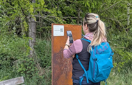 Audiotrack scannen am Roßkopfsteig Wanderin vor Stele mit QR-Code