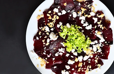 Ein Teller mit aufgeschnittener Rote Beete und Ziegenkäse, garniert mit Walnüssen und Salat