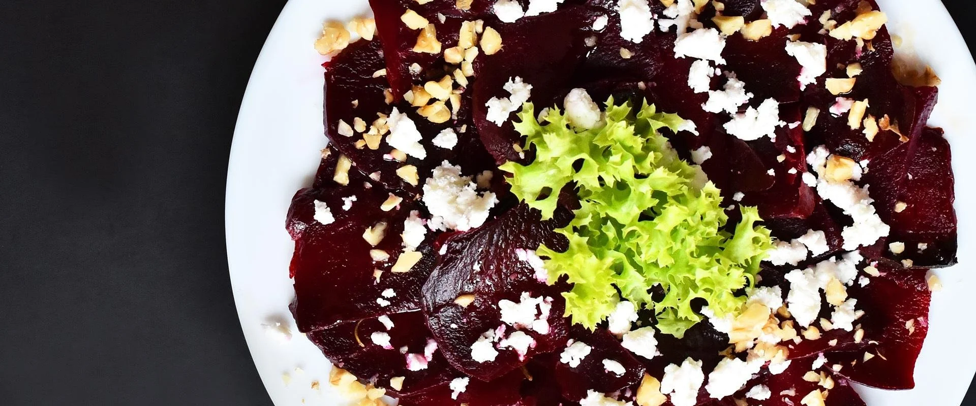 Ein Teller mit aufgeschnittener Rote Beete und Ziegenkäse, garniert mit Walnüssen und Salat