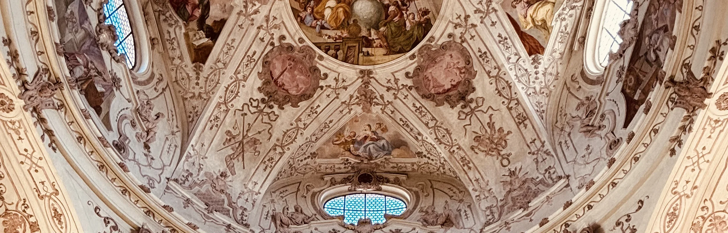 Innenansicht einer Kirche mit bemalter Kuppel und verzierten Wänden im Barockstil