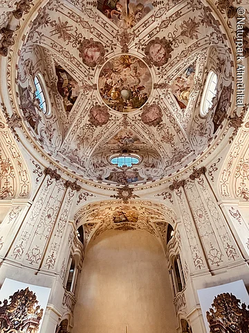 Innenansicht einer Kirche mit bemalter Kuppel und verzierten Wänden im Barockstil