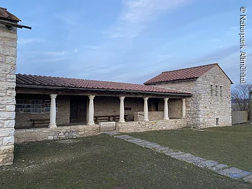Villa Rustica in Möckenlohe Steinernes Gebäude mit Säulen und rotem Ziegeldach vor bewölktem Himmel und Rasenfläche