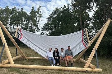 vier Erwachsene sitzen am Rand der Hängematte